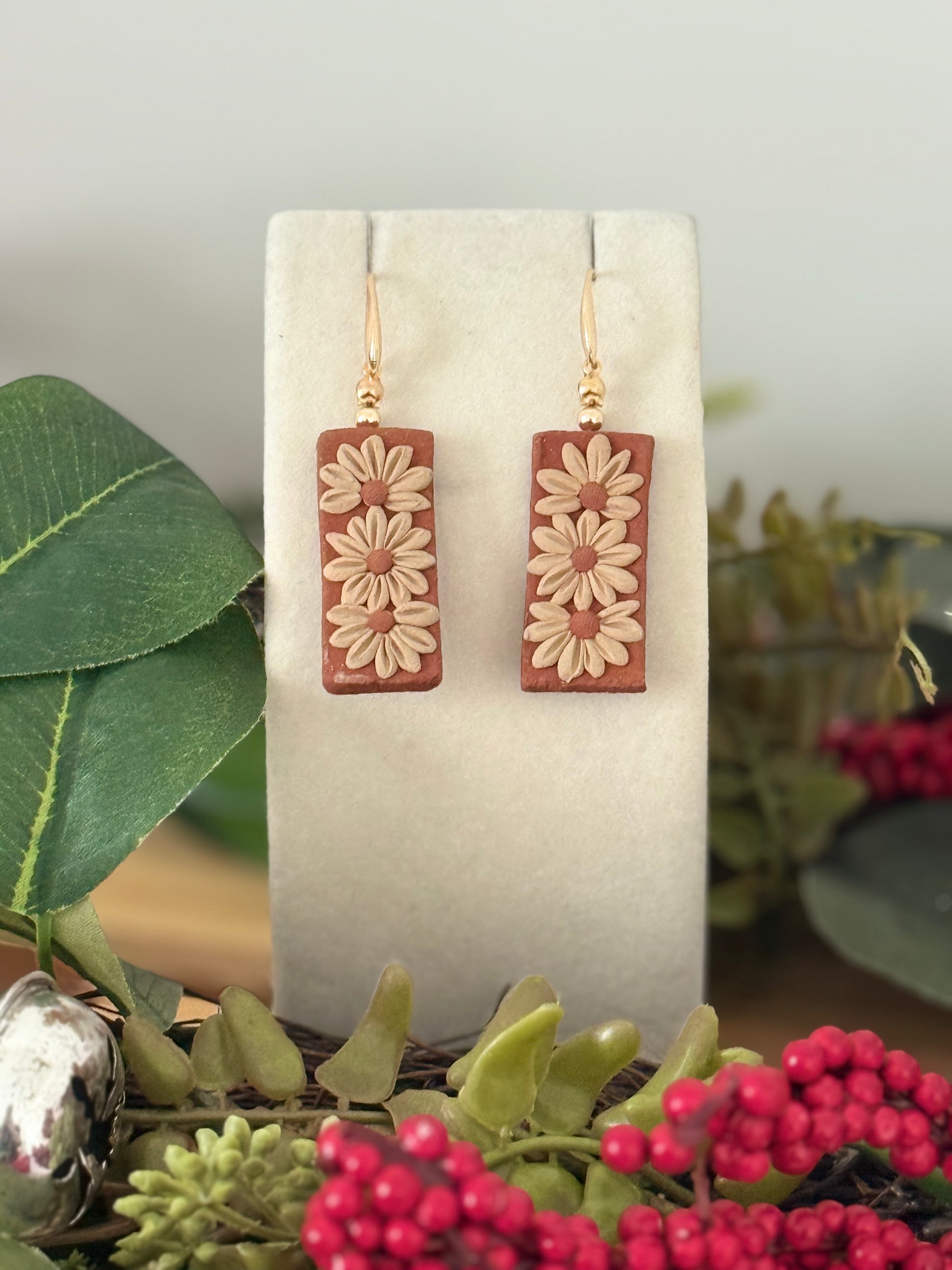Rectangular earrings with floral design on a white card with greenery and berries in the background