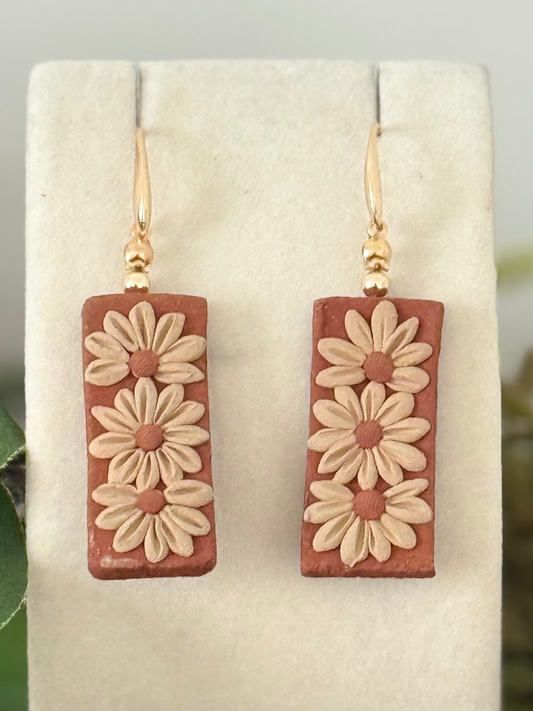 Rectangular earrings with floral design on a white card with greenery and berries in the background